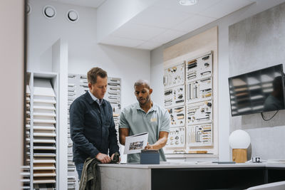 Salesman discussing with mature man over brochure at store