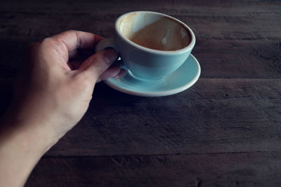 Hand holding coffee cup on table