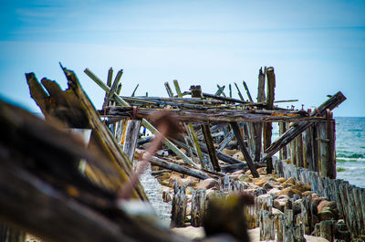 Damaged wooden post in sea against sky