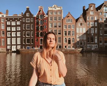 Young woman standing by river in city