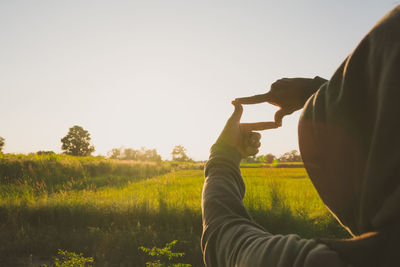 Close-up of man making finger frame against sky