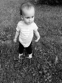Cute baby girl standing on field