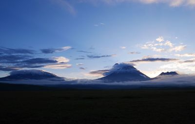 Scenic view of mountains covered with clouds against sky at dusk