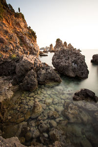 Rocks on sea shore against clear sky