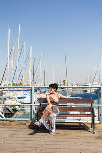 Young woman sitting on sailboat in sea against clear sky