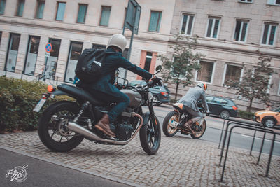 Man riding bicycle on street against building in city