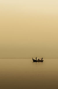 Silhouette boat sailing in sea against sky during sunset