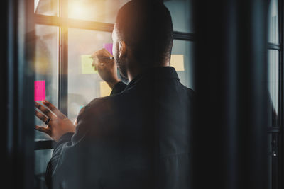 Side view of man looking through window