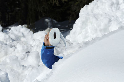 Cropped image of man holding toilet paper in snow