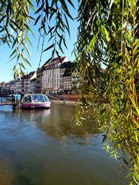 Boats moored on river by buildings against sky