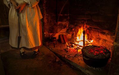 Low section of woman standing with tool by fireplace