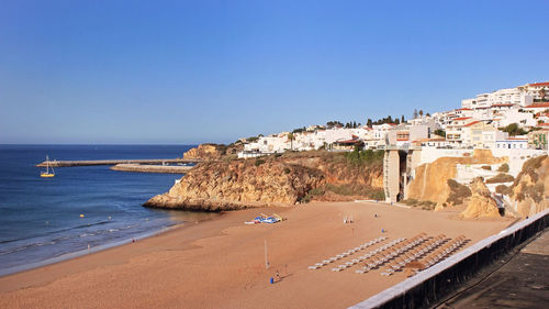 Buildings by sea against clear blue sky