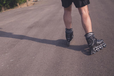 Low section of man rollerskating on road