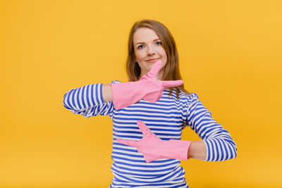 Portrait of smiling young woman against yellow background