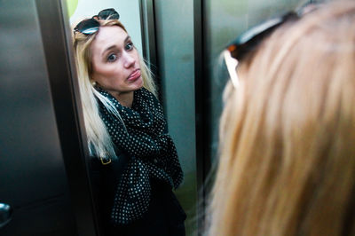 Reflection of young woman standing in elevator
