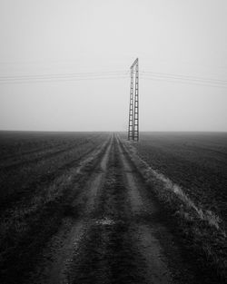 Electricity pylon on field against sky