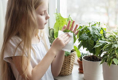 Girl cleaning plant leaf at home