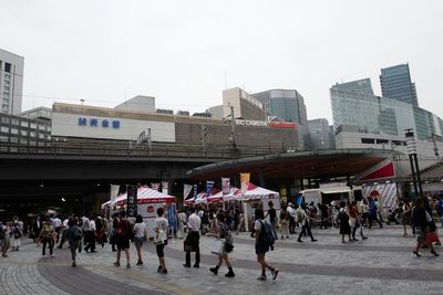 People walking on street in city against clear sky