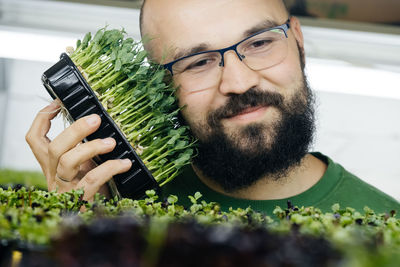 Young male farmer growing microgreens on indoor vertical garden. man small business owner
