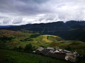 High angle view of houses by mountains against cloudy sky