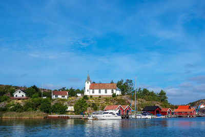 Houses by building against blue sky