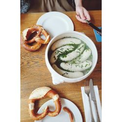 High angle view of woman eating fresh weisswurst and pretzel on table