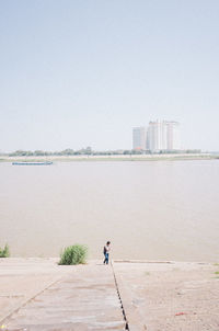 Rear view of people by sea against sky in city