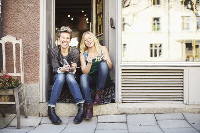 Full length portrait of female tailors sitting at studio doorway