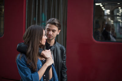 Couple looking at each other while standing against train in city