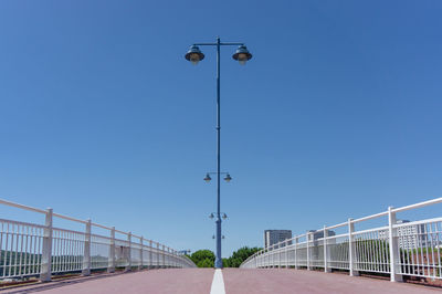 Street light on bridge against clear blue sky
