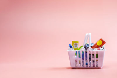 High angle view of multi colored bottles against pink background