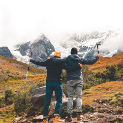 Rear view of hikers looking at snow covered mountains during winter