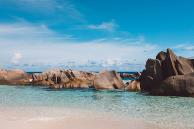 Rocks by sea against blue sky