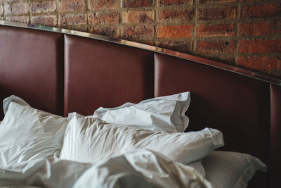 Close-up of messy bed against wall at home