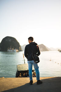 Young man standing on sea against clear sky