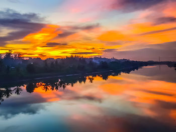 Scenic view of lake against dramatic sky during sunset