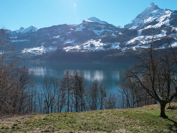 Scenic view of lake by snowcapped mountains against sky