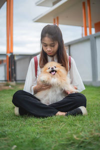 Woman with dog sitting on grass