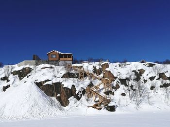 Houses on snowcapped mountain against clear blue sky