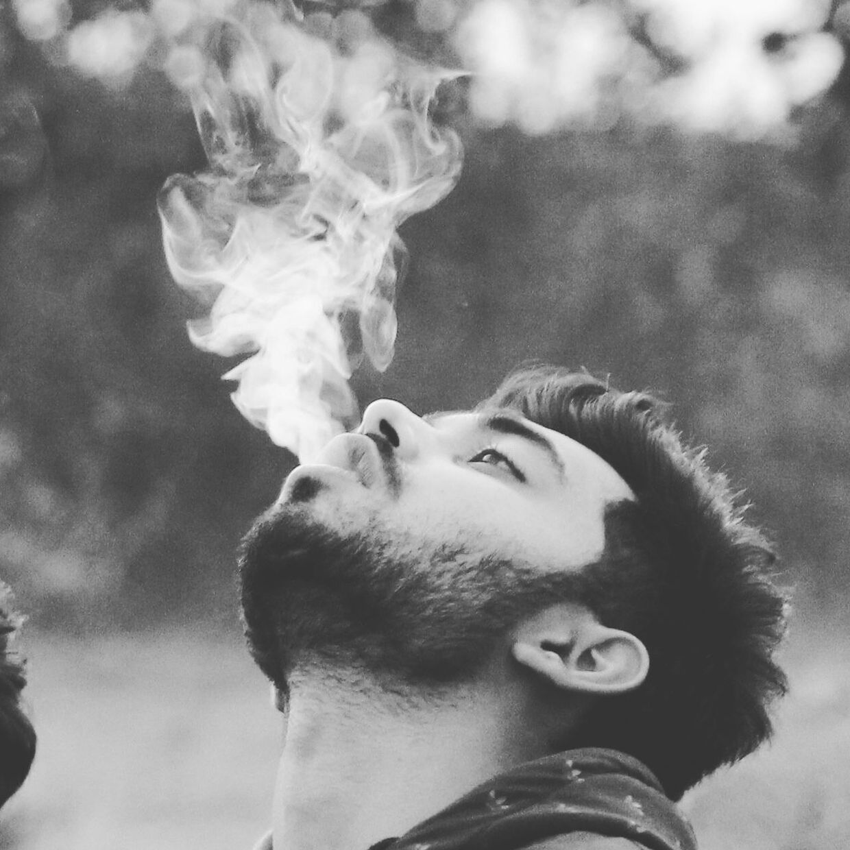 CLOSE-UP OF YOUNG MAN SMOKING CIGARETTE OUTDOORS