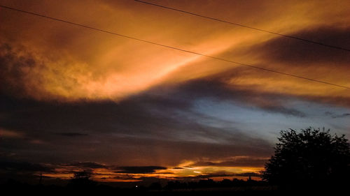 Silhouette trees against cloudy sky during sunset