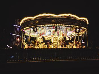 Low angle view of illuminated carousel against sky at night