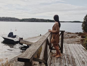 Rear view of woman looking at lake against sky