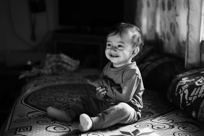 Portrait of cute girl sitting on bed at home