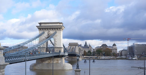 Bridge over river against cloudy sky