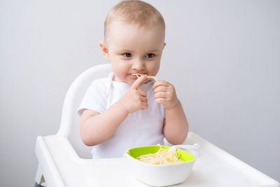 Portrait of cute baby boy eating food at home