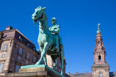 Low angle view of statue of building against blue sky