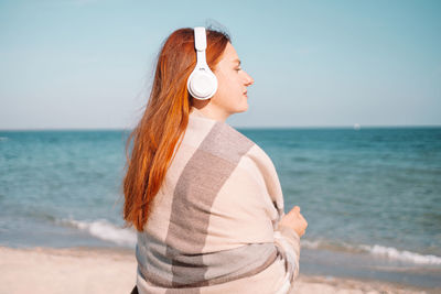 Rear view of woman standing at beach