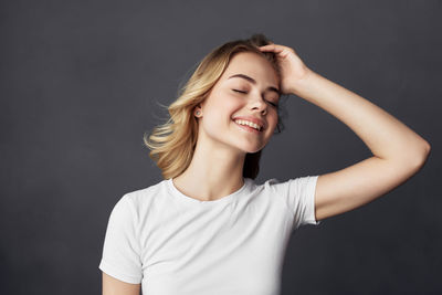 Portrait of smiling young woman against black background