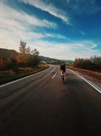 Rear view of man riding bicycle on road